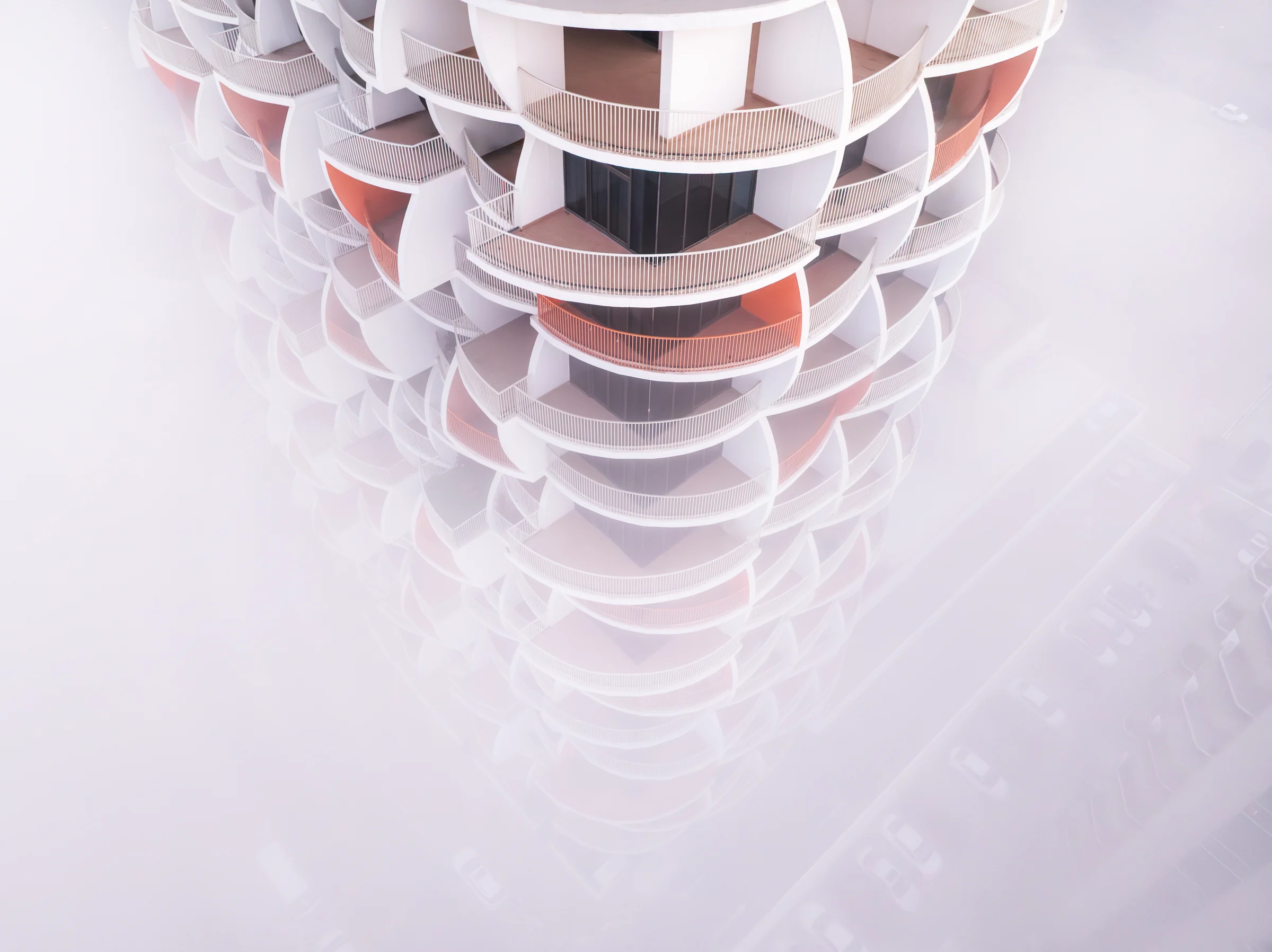 Aerial view looking down on a Binghatti tower at Dubai Silicon Oasis, its balconies rising out of fog