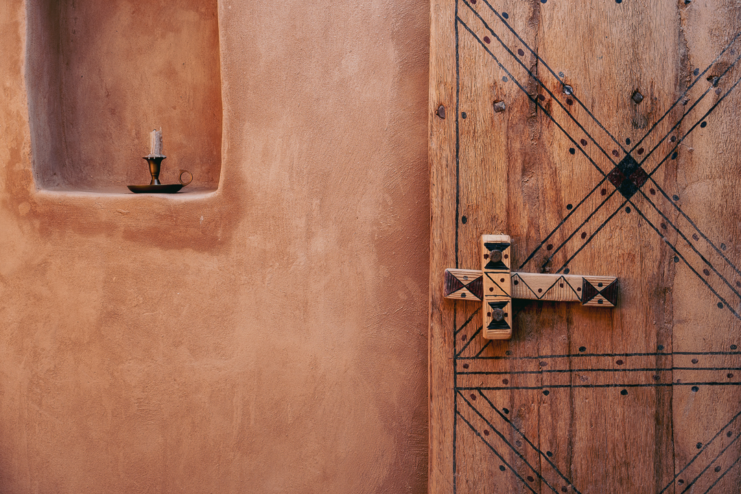 Carved timber door detail against mud brick, Dar Tantora The House Hotel, AlUla Old Town