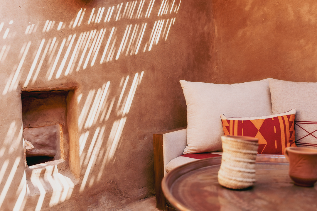 Light through a shuttered opening across a restored mud brick interior, Dar Tantora, AlUla Old Town