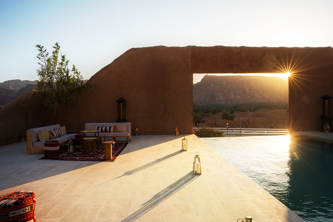 Sunset through a mud brick archway onto the pool terrace, Dar Tantora The House Hotel, AlUla Old Town