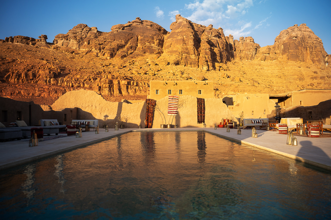The rooftop pool at Dar Tantora The House Hotel, AlUla, with the sandstone canyon behind at golden hour